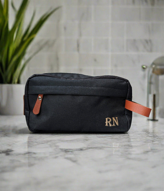 Men's black toiletries bag with brown accents. Monogramed initials in gold on bottom right corner https://wattlelanedesigns.com.au/products/mens-monogramed-toiletries-bag-black