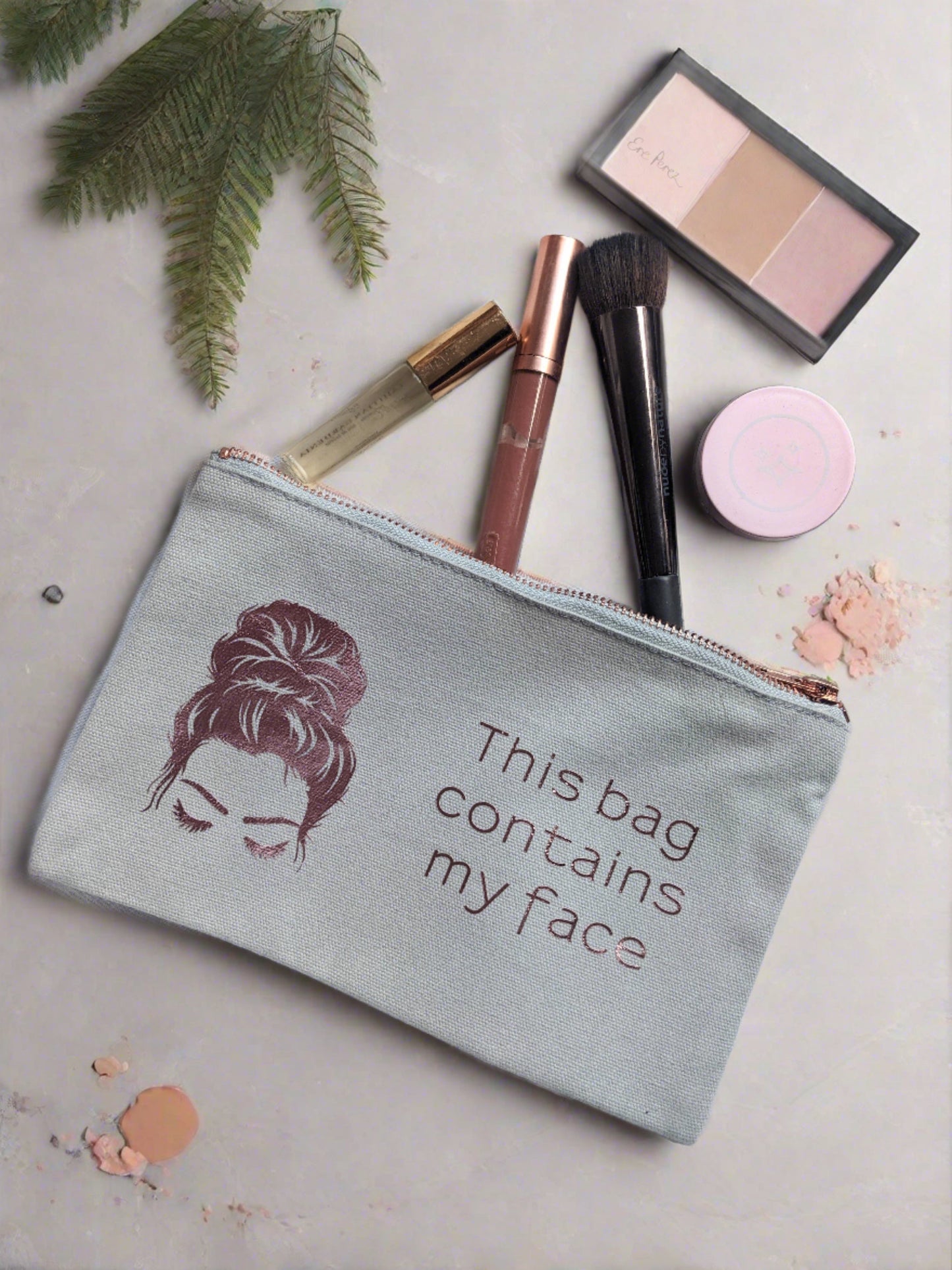 light grey rectangle shape makeup make with rose gold zip, waterproof internal lining and image in rose gold of womans head with eyes closed and bun in her hair https://wattlelanedesigns.com.au/products/this-bag-contains-my-face-make-up-bag