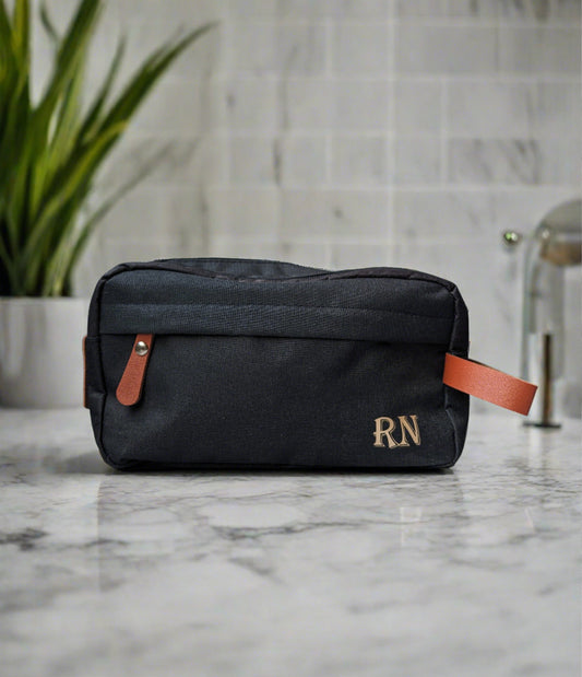 Men'sblack toiletries bag with brown accents. Monogramed initials in gold on bottom right corner https://wattlelanedesigns.com.au/products/mens-monogramed-toiletries-bag-black